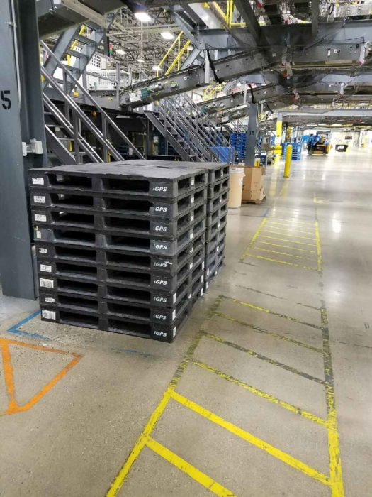 Idle plastic pallets stacked in a warehouse.