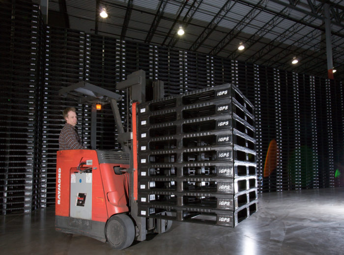 Forklift lifting plastic pallets in a warehouse
