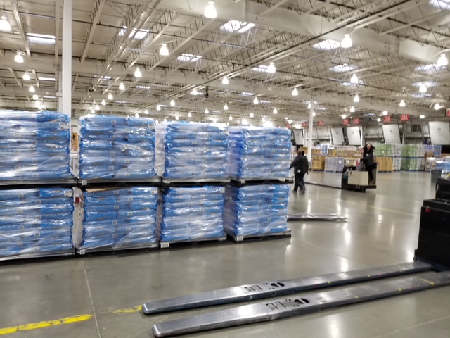 A forklift is parked in front of a line of stacked pallets.